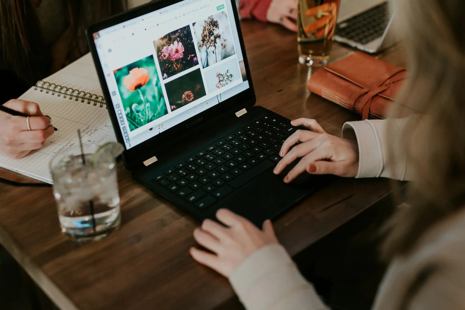 Laptop, anteckningsbok och kaffe på ett arbetsbord.